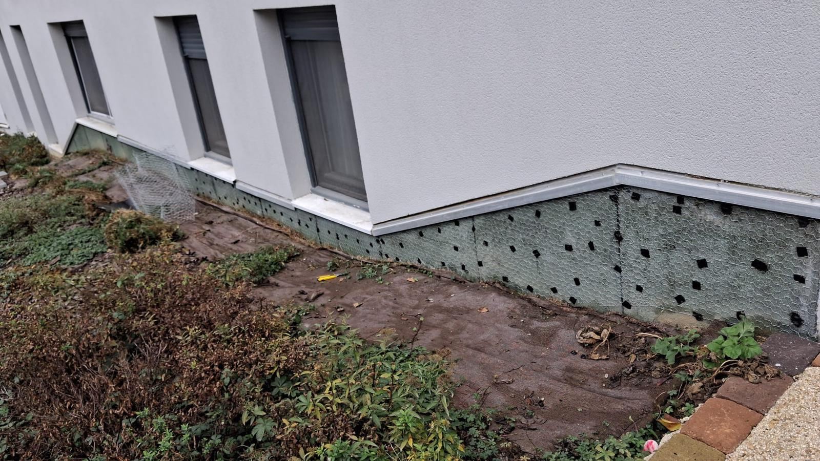 Soubassement d’une résidence protégé par un grillage et un géotextile, avant reprise
