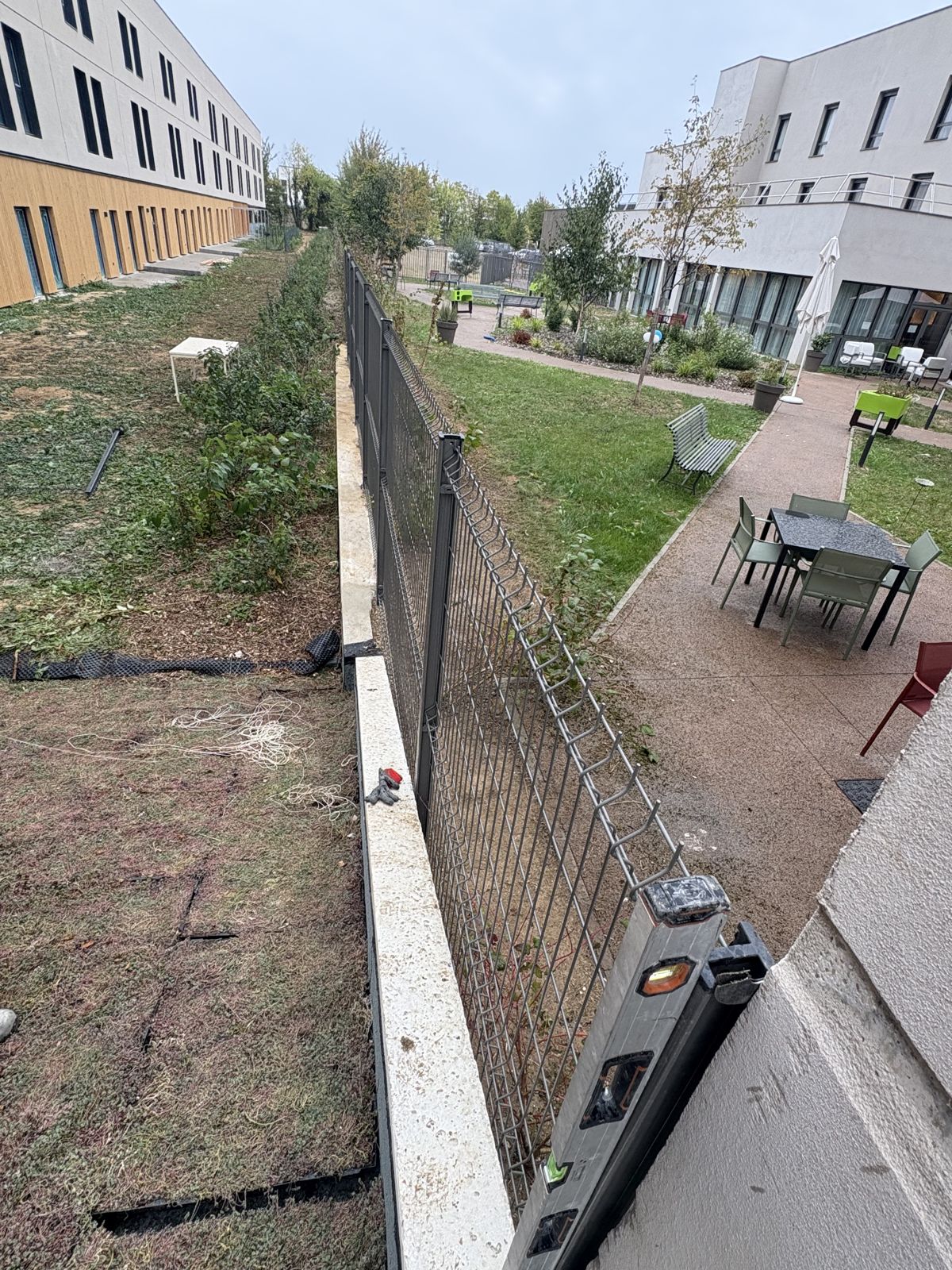 Espaces verts et terrasse d’une résidence, le long de la clôture